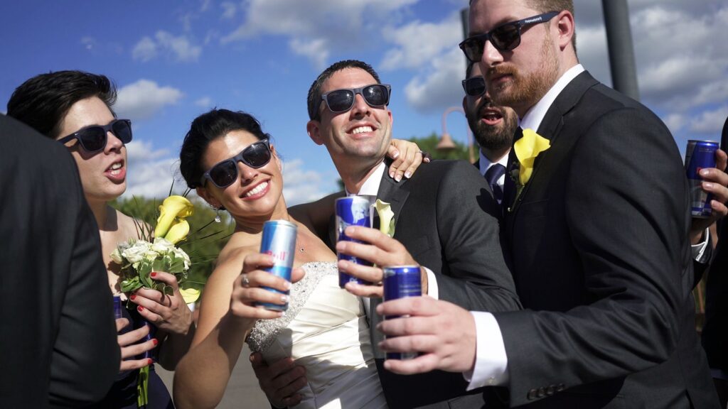 Minneapolis Radisson Blu Wedding Bride and Groom and Wedding Party have Redbull on Stone Arch Bridge