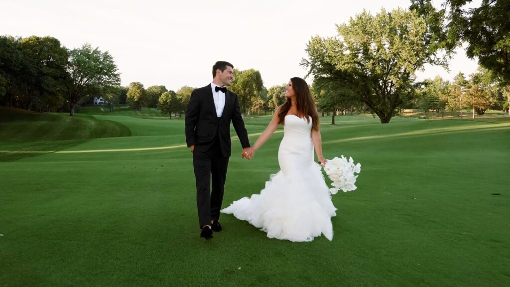 Bride and groom walking across the golf course at sunset during golden hour